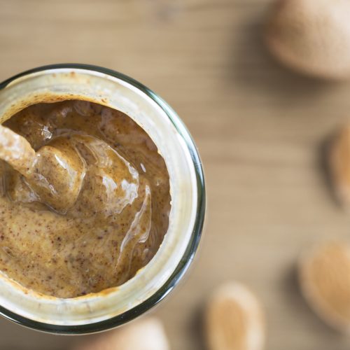 Almond Butter in jar with spoon, from directly above