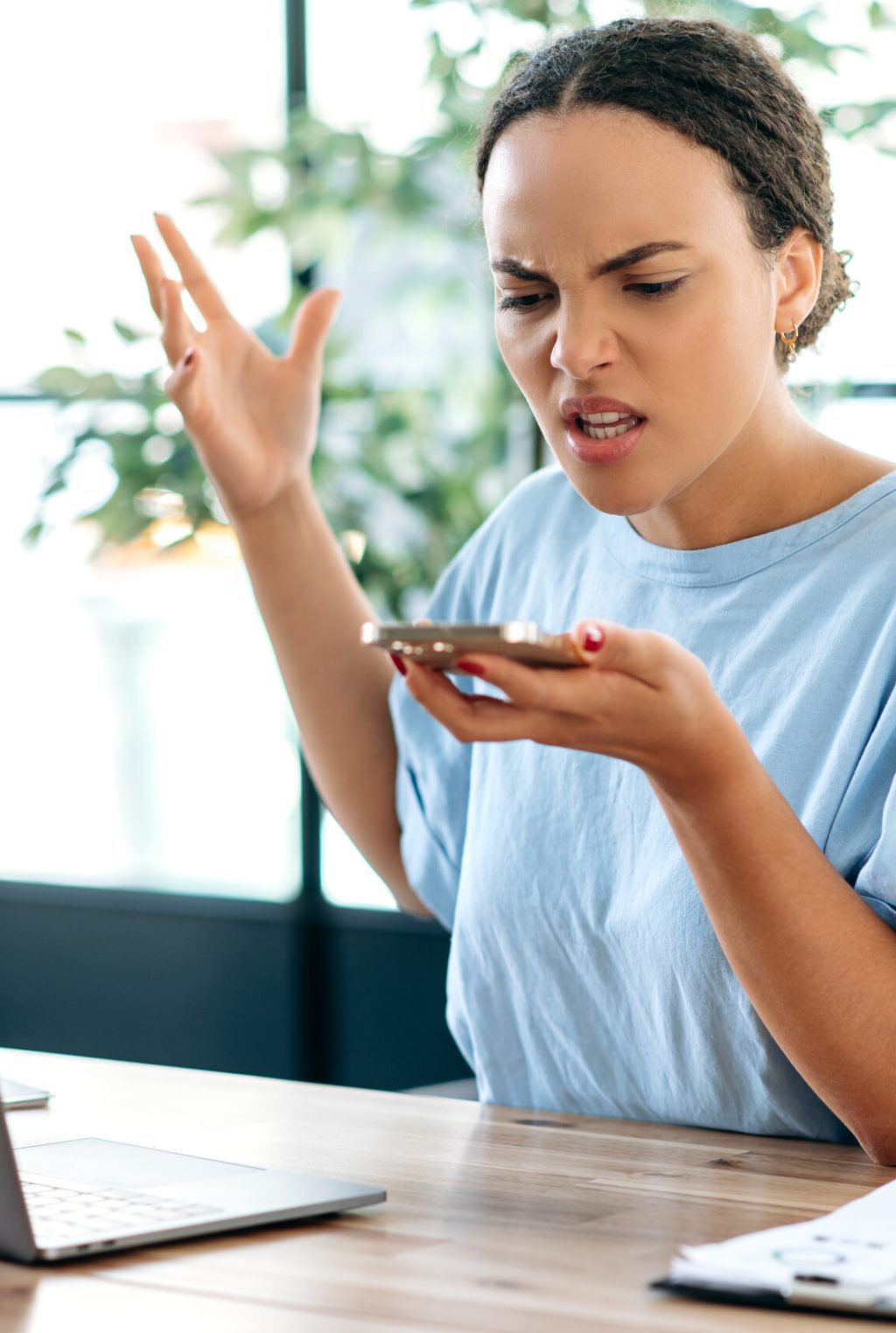 Annoyed angry young brazilian or latino business lady, company director, supervisor, yells irritably while speakerphone conversation, gesturing with hand, annoyed by poor performance of employees